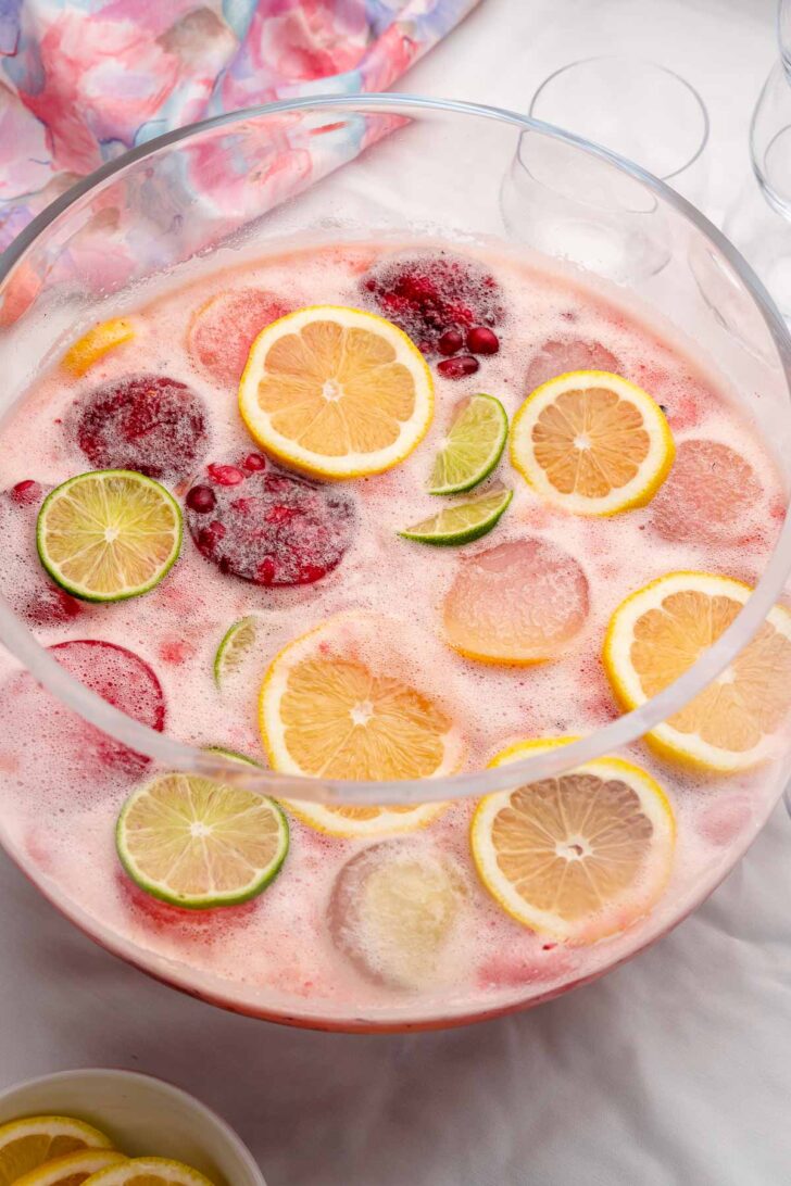Glass punch bowl of punch with lemons, limes and fruit ice molds.