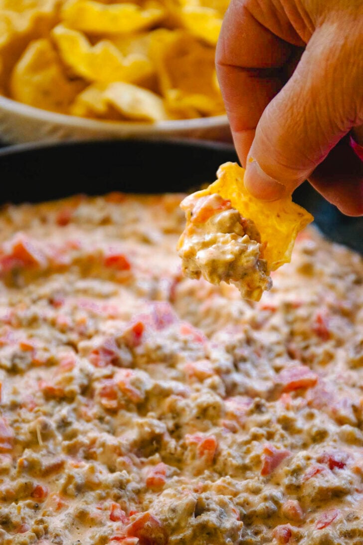 A chip with a chunk of homemade sausage dip on it ready to eat.