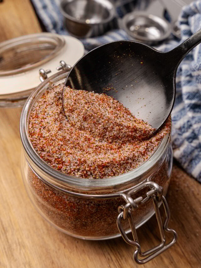 House seasoning blend in a small mason jar with a black spoon scooping some out.