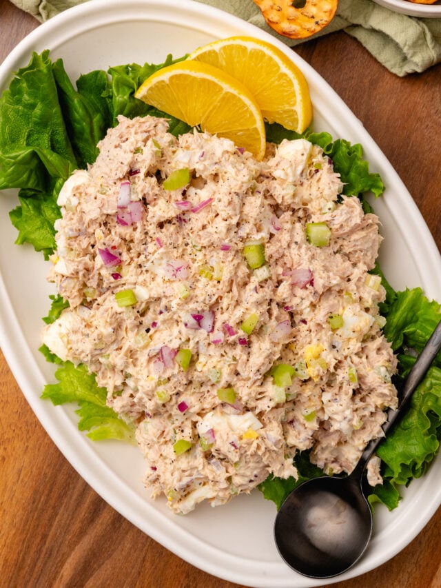 Tunsa salad placed on a green lead of lettuce sitting on a place with fresh lemon slices.