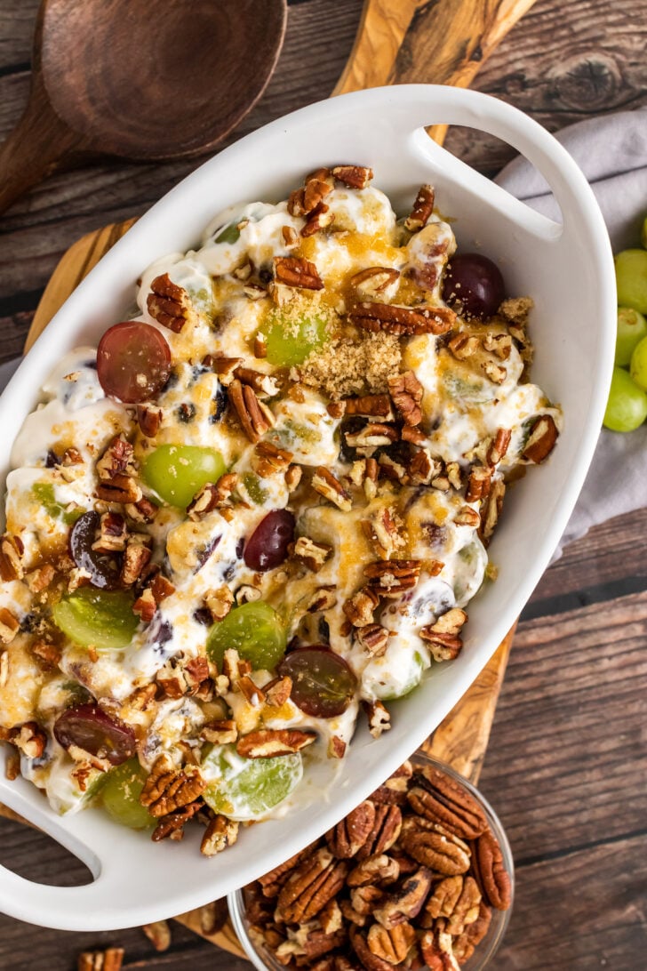 Grape Salad with chopped pecans in a white bowl topped with brown sugar.