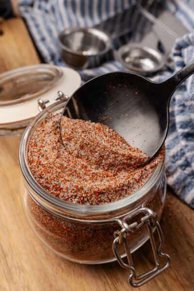 House seasoning blend in a small mason jar with a black spoon scooping some out.