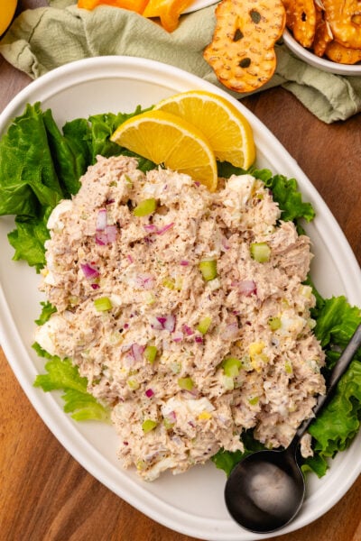 Tunsa salad placed on a green lead of lettuce sitting on a place with fresh lemon slices.