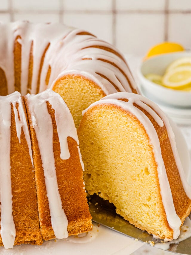 Slice of lemon pound cake being taken out with a nice drizzle of lemon icing on top of it.