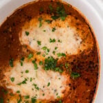 Crock Pot Chicken Parmesan with melted cheese and marinara sauce in white bowl, garnished with fresh parsley