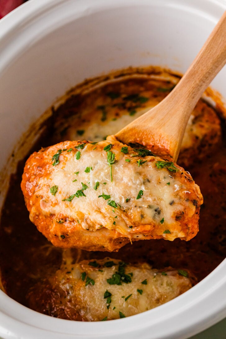 Four-step process collage for slow cooker Chicken Parmesan — pouring marinara sauce into a white Crock Pot, hand-breading chicken breasts in seasoned bread crumbs, layering the breaded chicken topped with shredded mozzarella over the sauce, and the finished cheesy chicken garnished with fresh parsley beside a bowl of spaghetti