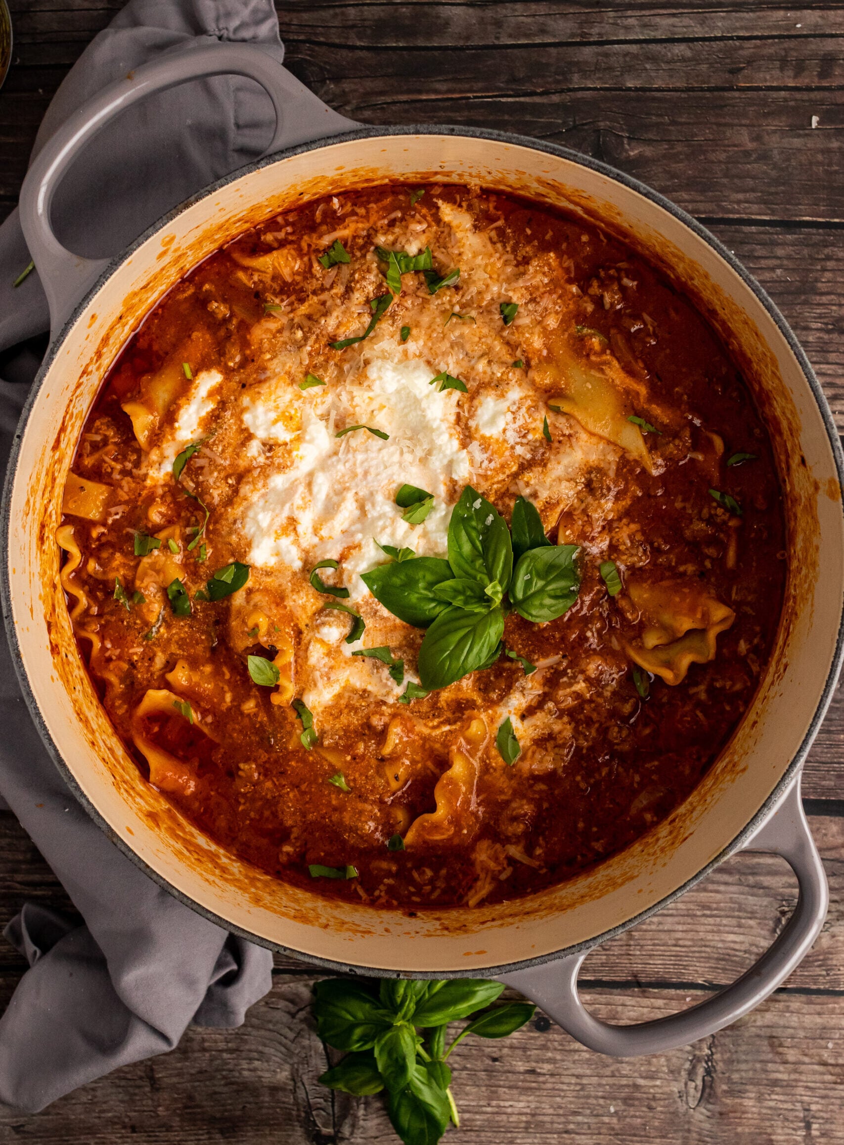 Creamy tomato pasta baked in gray cast iron Dutch oven, topped with melted mozzarella and fresh basil, exemplifying Beginners Guide To Cast