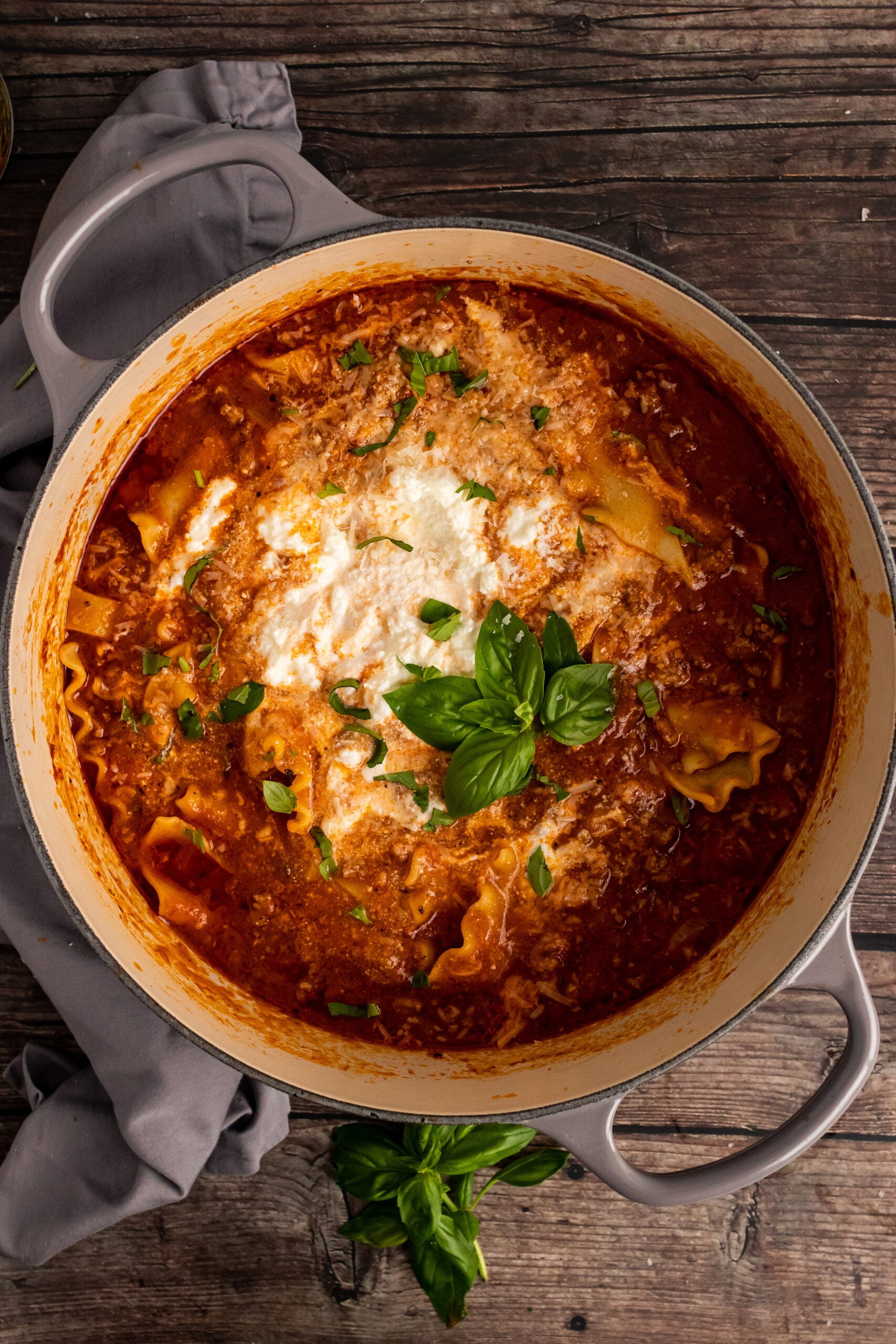 Creamy tomato pasta baked in gray cast iron Dutch oven, topped with melted mozzarella and fresh basil, exemplifying Beginners Guide To Cast