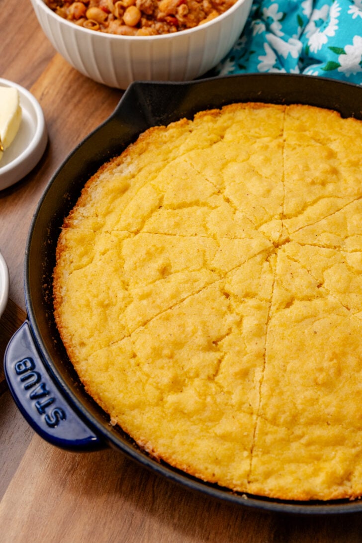 Cast iron skillet with baked cornbread cut into triangles for serving.
