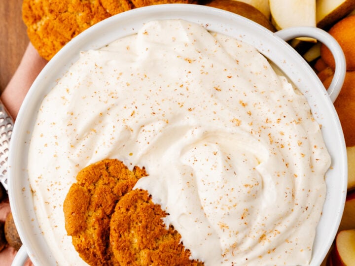 Eggnog dip 8 1 in white bowl with cinnamon sugar topping, served with gingersnap cookies and apple slices on wooden surface