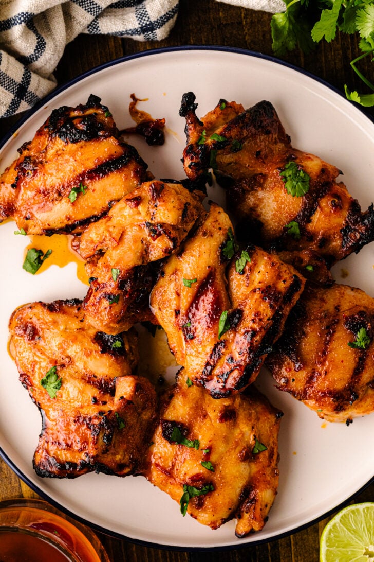 Honey Chipotle Grilled Chicken skewers arranged on white plate with fresh cilantro garnish and lime wedge on dark wood table