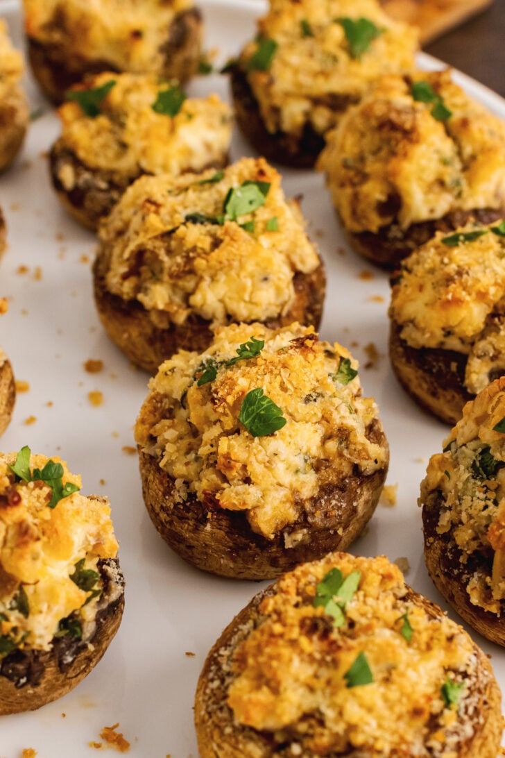 Cheese-stuffed mushrooms with parsley garnish on a plate.