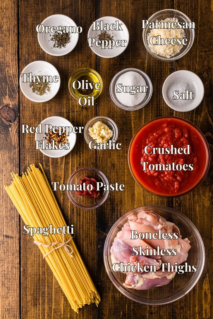 Ingredients for skillet chicken spaghetti laid out together—chicken, spaghetti, crushed tomatoes, tomato paste, garlic, dried herbs, red pepper flakes, and Parmesan—to show what you need for this one-skillet recipe.