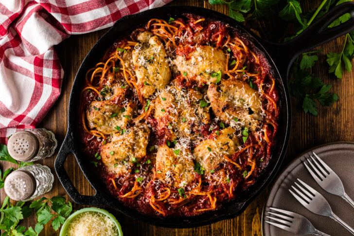 Skillet chicken spaghetti in a cast iron pan with creamy cheese sauce and diced tomatoes.