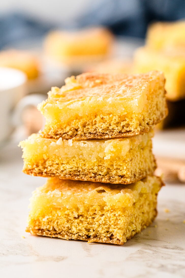 एक छोटी सी प्लेट पर नीमन मार्कस केक के चौकोर टुकड़े रखे हुए हैं, जिनमें नरम, अंदर से नम और हल्के कुरकुरे किनारे दिख रहे हैं, जो कॉफी के साथ परोसने के लिए तैयार हैं।