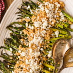 Oven roasted asparagus spears topped with crumbled feta cheese on a serving platter