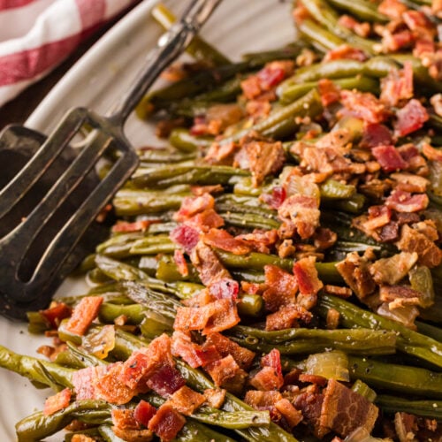 Crispy bacon-topped green beans on white plate with fork, cp maple greenbeans 14 side dish recipe