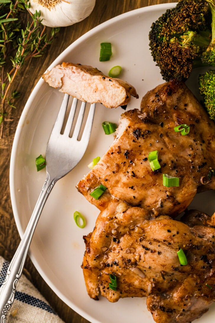 कटी हुई बाल्समिक चिकन जांघें पास से एक गहरी कारमेलाइज्ड, चमकती हुई सतह दिखाती हैं जिसमें पूलिंग बाल्समिक कमी होती है।