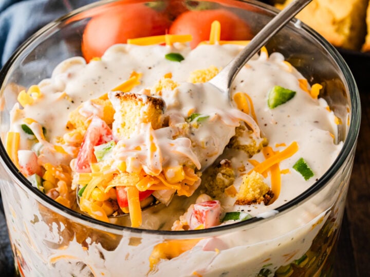 Southern Cornbread Salad in glass bowl with creamy dressing, shredded cheese, tomatoes, and green onions garnish