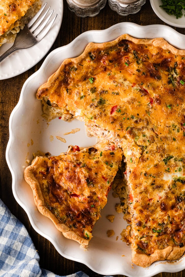 A whole pimento cheese sausage quiche fresh from the oven in a deep dish pie crust, golden brown on top and set perfectly in the center, ready to slice and serve.