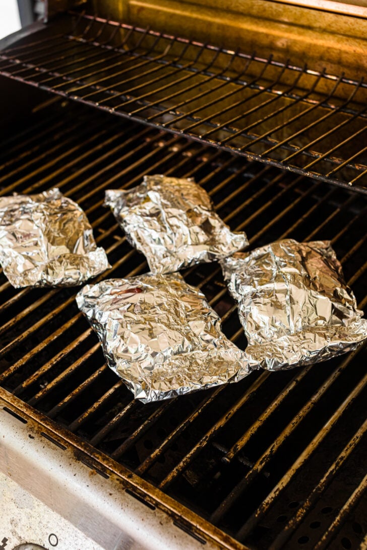 Wrapped hobo dinner foil packs cooking on an oven rack.