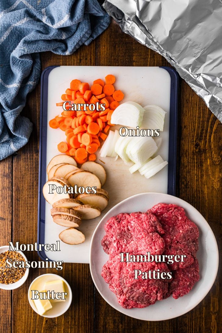 Ingredients for hamburger hobo dinner foil packs, including beef patties, potatoes, carrots, onions, butter, and Montreal seasoning.