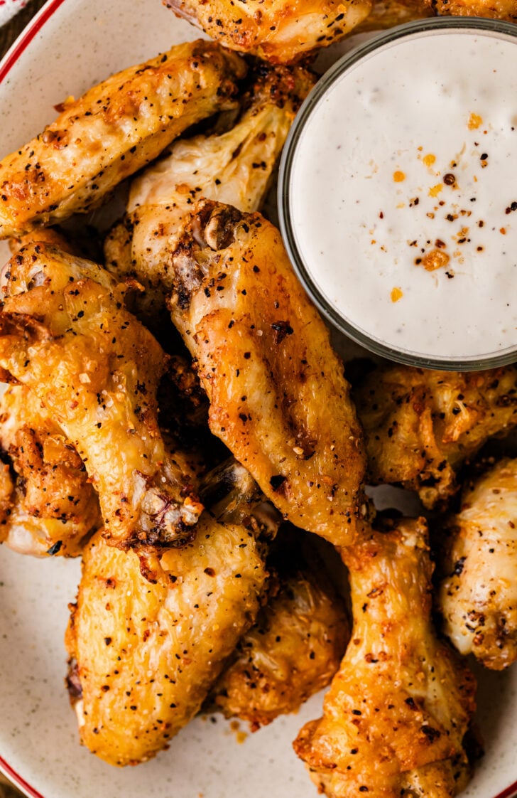 Platter of crispy, golden seasoned air fryer chicken wings with a bowl of ranch dipping sauce.