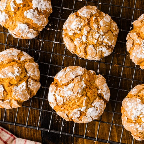 Overhead view of pumpkin crinkle cookies dusted with powdered sugar on a wire cooling rack.