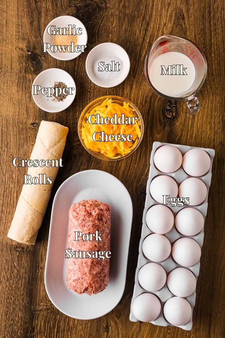 Ingredients for egg and sausage breakfast casserole, including eggs, sausage, cheese, and crescent roll dough.